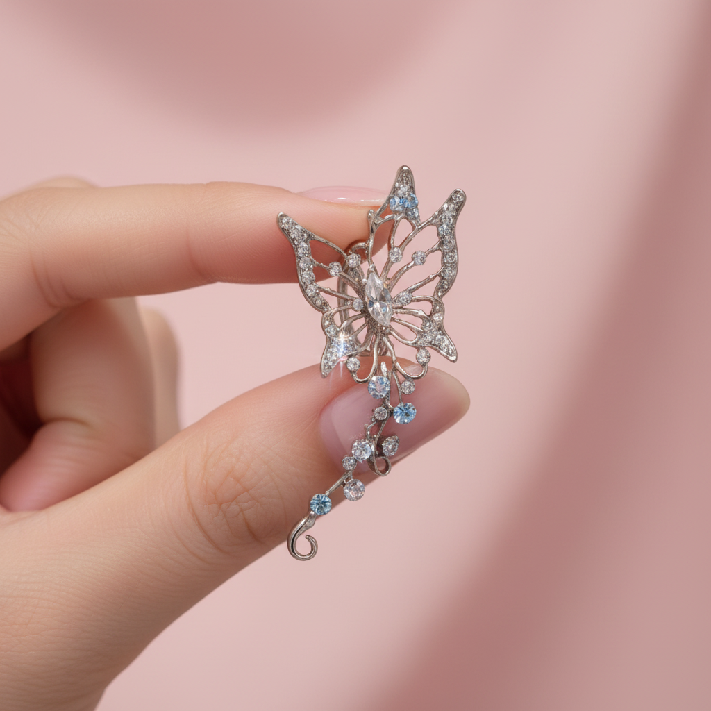 Crystal butterfly ear cuff held in hand, blush pink background